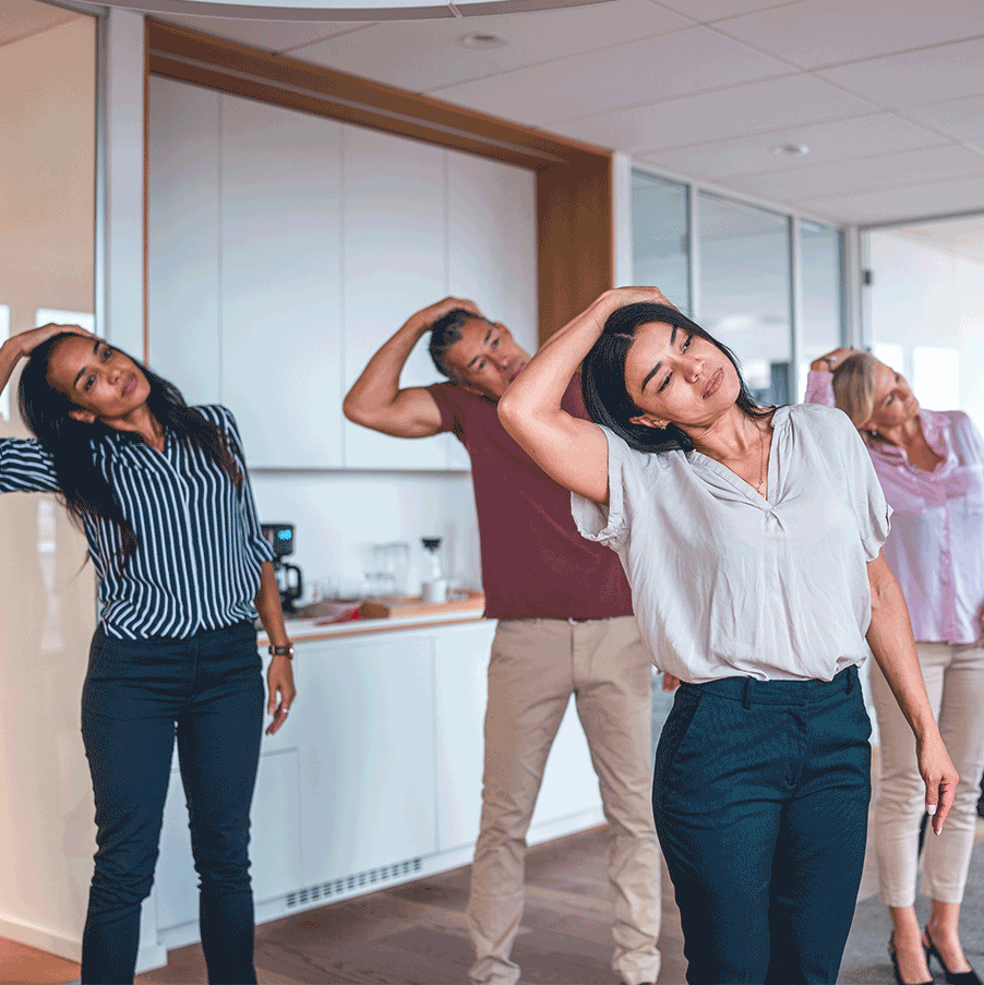 Mitarbeiter nehmen an einem vor Ort stattfindenden Firmenfitnesskurs teil und führen Dehnübungen in einem modernen Büro durch, um das Wohlbefinden am Arbeitsplatz zu fördern.