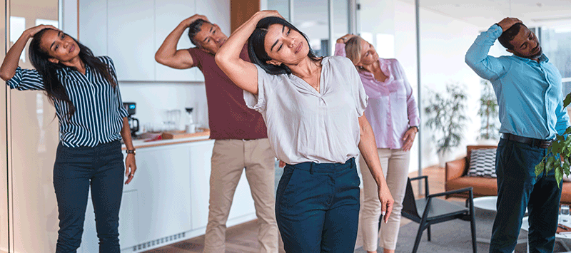 Mitarbeiter nehmen an einem vor Ort stattfindenden Firmenfitnesskurs teil und führen Dehnübungen in einem modernen Büro durch, um das Wohlbefinden am Arbeitsplatz zu fördern.